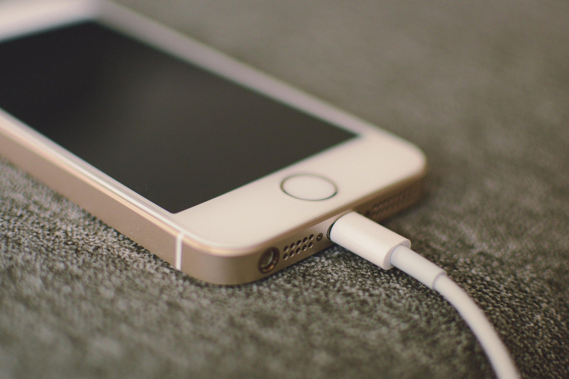 A smartphone charging on a desktop surface.